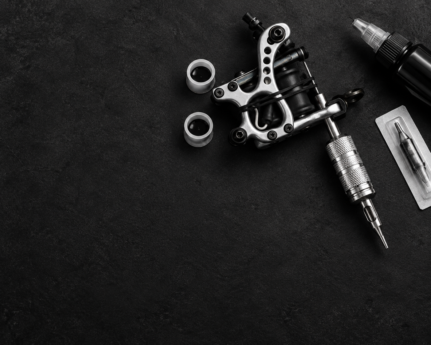 Tattoo machine and studio tools arranged on a dark workbench